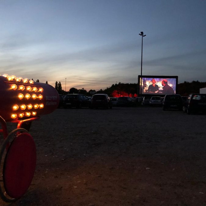 Billy Boy Autokino: Links steht die beleuchtete Sackkarre, vorne stehe die ganzen Autos im Autokino bei Dunkelheit.