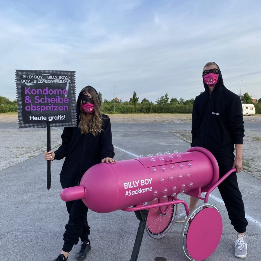 Billy Boy Autokino: Die beiden Promoter stehen mit der Sackkarre und einem Schild in der Hand auf dem Parkplatz.