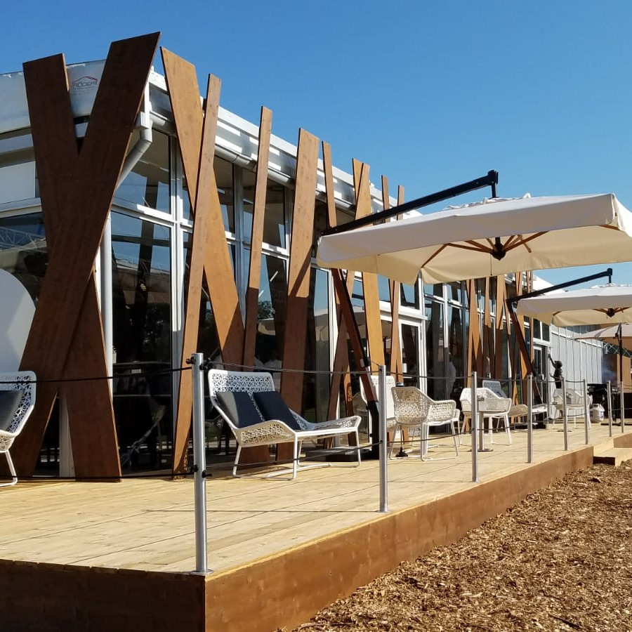 BMW Group: Blick auf die Terrasse von der Seite. Auf der Terrasse stehe Sitzmöglichkeiten und große Schirme.