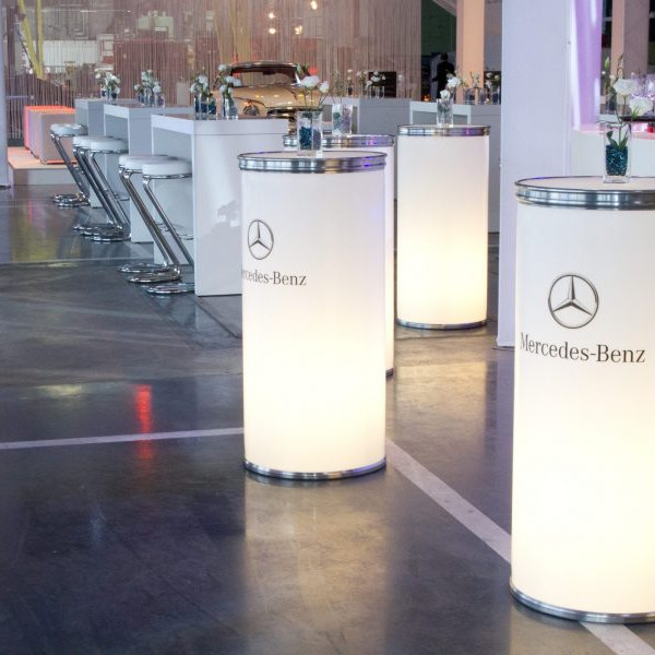Daimler 75 Jahre PKW: Vor der Bar stehen weiße runde Stehtische mit dem Schriftzug Mercedes Benz.