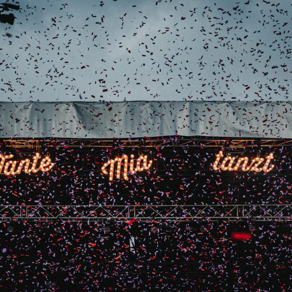 Tante Mia Tanzt: Konfettiregen vor beleuchtetem Festivallogo bei Dämmerung