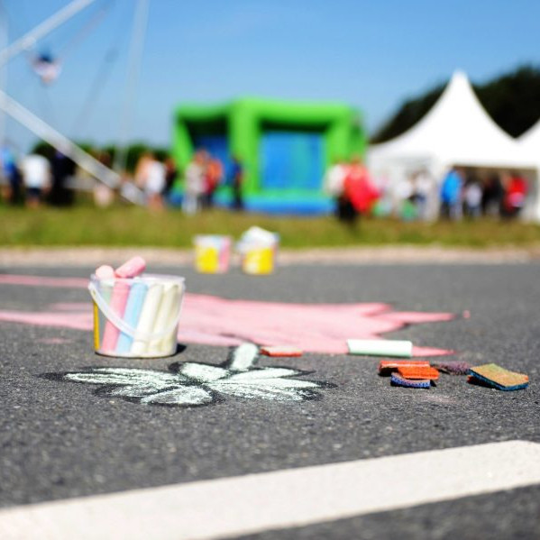 Göbber Mitarbeiterfrühstück: Auf der Strasse ist ein kleines Schmetterling mit Kreide gemalt. Daneben steht ein kleiner Eimer mit Kreide.