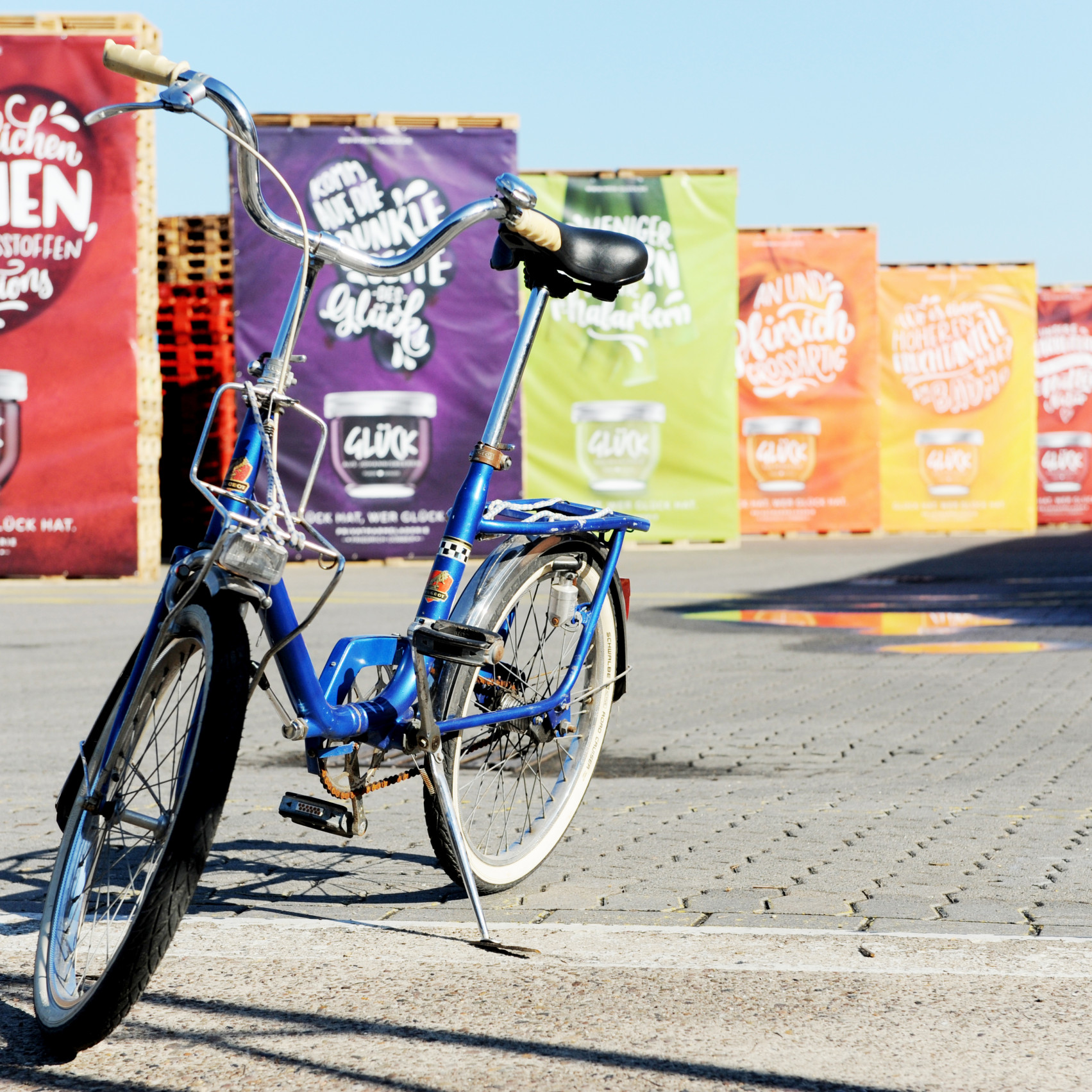 Göbber Mitarbeiterfrühstück: Ein Klapprad vor Pallettentürmen an denen Banner hängen