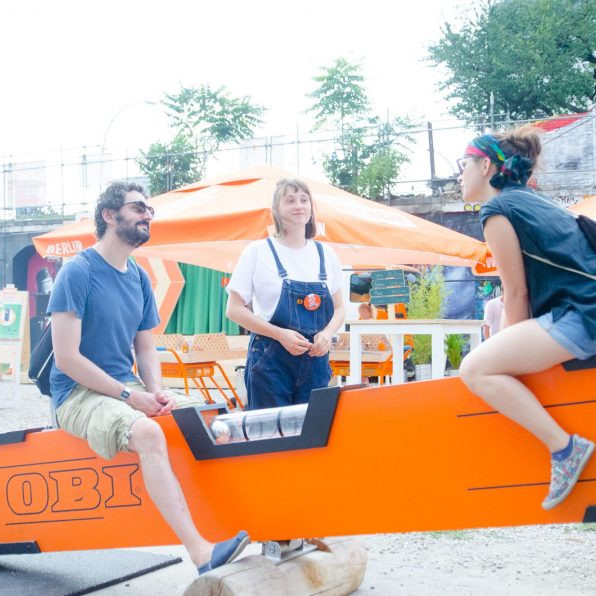 OBI MachBar Roadshow: Zwei Personen sitzen auf einer Wippe die aussieht wie eine Wasserwaage.