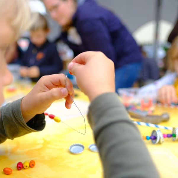 OLB 150 Jahre Festival: Ein Kind versucht bei einer Mitmachaktion einen Faden in eine Nadel einzufädeln