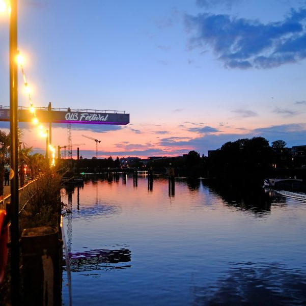 OLB 150 Jahre Festival: Abendlicher Blick über den Fluss Hunte, im Hintergrund steht der große beleuchtete Kran.